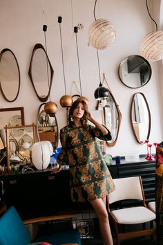 a woman standing in front of a mirror with her hands on her head and looking at the camera