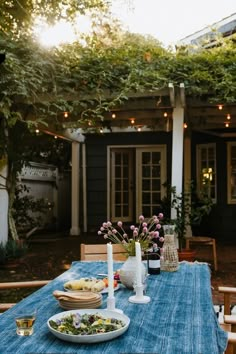 a blue table cloth with plates of food on it in front of an outdoor dining area