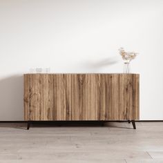 a wooden cabinet sitting on top of a hard wood floor next to a white wall