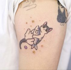 a woman with a cat tattoo on her arm and shoulder, holding onto another cat's tail