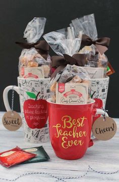 two red coffee mugs filled with cookies and tea bags sitting on a white table