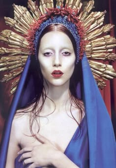 a woman wearing a blue and red headdress with gold spikes on her head