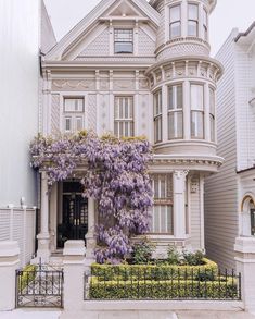 a large house with purple flowers on the front