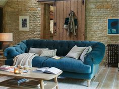 a living room with a blue couch and coffee table in front of a brick wall