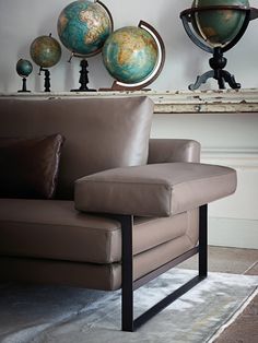 a brown leather chair sitting on top of a rug next to a wall mounted globe