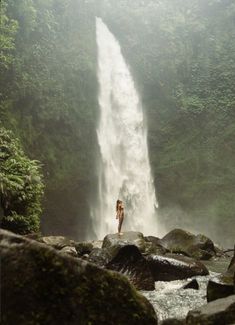 a woman standing in front of a waterfall