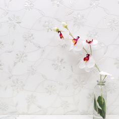 a vase with some flowers in it on a table next to a wallpapered background