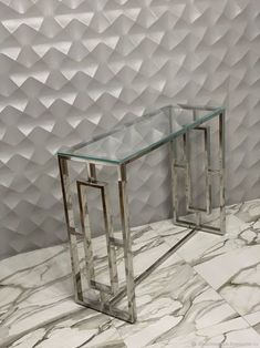 two glass tables sitting on top of a marble floor next to a wall covered in paper