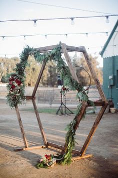 a wooden structure with greenery and flowers on the ground in front of string lights