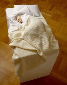 an overhead view of a person sleeping in a bed with white sheets and blankets on it