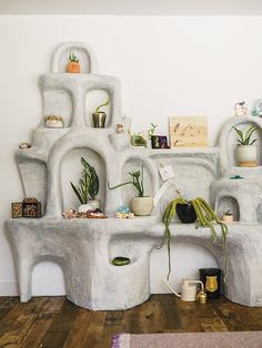 a room filled with pots and plants on top of white shelves next to a wooden floor