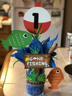 a vase filled with blue flowers sitting on top of a table next to a sign that says gone fishing