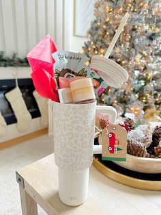 a christmas tree is in the background behind a coffee cup with holiday decorations on it