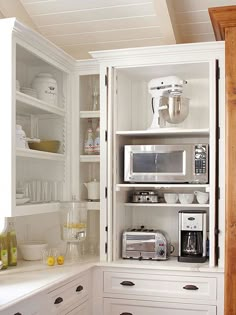 a kitchen with white cupboards filled with appliances