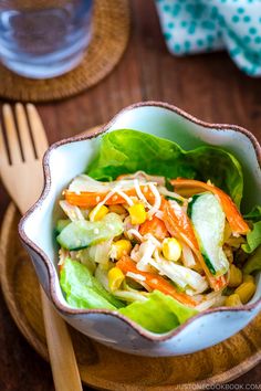 a salad with lettuce, carrots and corn in a bowl on a wooden table