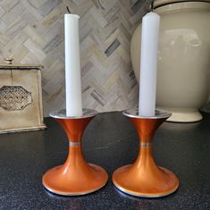 two candles sitting on top of a table next to a vase with a white candle in it