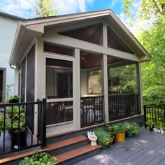 a screened porch with potted plants on the side and stairs leading up to it