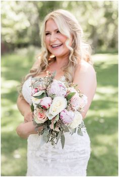 a woman in a wedding dress holding a bouquet of flowers and smiling at the camera