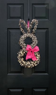 a black door with a pink bow and wreath hanging on it's front side