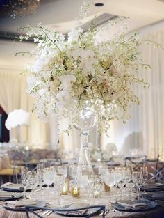 an image of a table setting with white flowers in a vase on the centerpiece