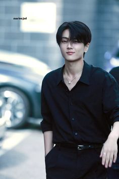 a young man walking down the street with his hand on his hip and wearing a black shirt