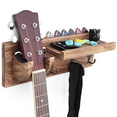 a guitar is hanging on the wall next to a rack with shoes and other items