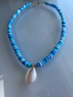 handmade blue and white clay bead necklace with shell charm perfect for summer! Clay Beads Ideas Necklace, Blue Clay Bead Necklace, Beaded Summer Necklace, White Clay Bead Necklace, Bracelet Making Business, Beach Bracelet Ideas, Clay Bead Brackets, Clay Bead Necklace Ideas, Bead Brackets