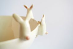 two small white deer figurines sitting in a bowl