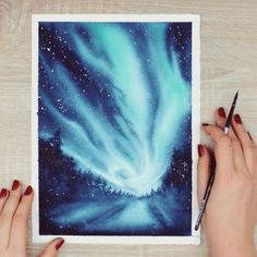 two hands holding a pencil and drawing an aurora bore