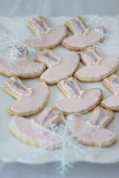 decorated cookies with frosting and pink icing are on a white plate next to snowflakes