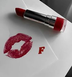 a red lipstick is laying on top of a piece of paper with the letter f