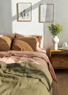 a bed sitting in a bedroom next to a wooden table with a potted plant on it