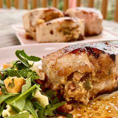 a white plate topped with meat covered in gravy next to a green salad