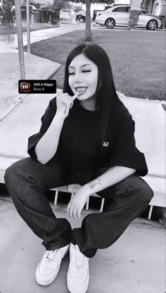 a woman sitting on top of a bench in front of a building with her hand near her mouth