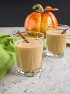 vegan gf pumpkin smoothie with cinnamon sticks in the glass and an orange pumpkin behind it