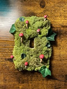 the letter b is made out of moss with mushrooms and leaves around it on a wooden surface