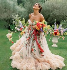 a woman standing in the grass with flowers on her dress