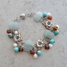 Mixed beading elements are linked in this floral beaded silver bracelet. Wire wrapped aventurine beads are accented with dangles of turquoise magnesite beads, white freshwater cultured pearl beads and amber glass beads.  A playful and colorful bracelet that gives a tropical beach vibe to the mix of elements.  Bracelet has a magnetic closure.  Magnetic closures make for easy open close feature and fit on the bracelet, but they are magnetic.   if you prefer a lobster claw closure on this bracelet I will be happy to make the substitution.  Just let me know with your order and I will make the change. The bracelet measures 7". If you need additional links for a different fit just send me a message with your order. All of my jewelry items come boxed and lace ribbon tied and tagged.  This bracele Pearl Bead Bracelet, Linked Bracelet, Green Beaded Bracelets, Colorful Bracelet, Bracelets Design, Turquoise Bead Bracelet, Beads Bracelet Design, Silver Bead Bracelet, Silver Bead