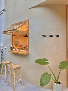 an open window on the side of a building with plants in pots and stools next to it