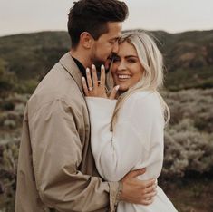 a man and woman standing next to each other with their hands on the foreheads