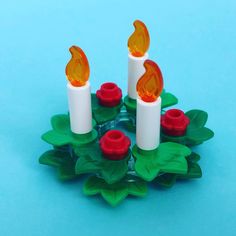 three lit candles sitting on top of green leaves