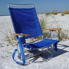 a blue lawn chair sitting on top of a sandy beach next to grass and sand dunes