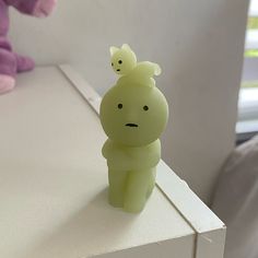 a small plastic toy sitting on top of a white table next to a stuffed animal