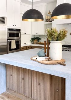 a kitchen island with two lights hanging over it and a potted plant on the counter