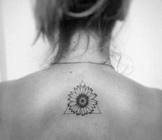 a black and white photo of a woman's back with a sunflower tattoo