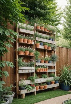 a wooden shelf filled with potted plants on top of grass next to a fence