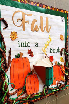 a sign that says fall into a book with pumpkins and leaves around it on the wall