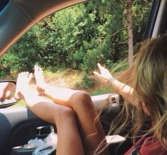 two people sitting in the passenger seat of a car with their feet out the window