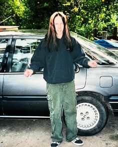 a man standing in front of a car with his arms out and eyes wide open