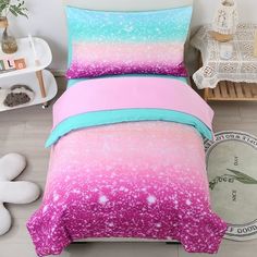 a bed with pink and blue bedspread in a room next to a white wall